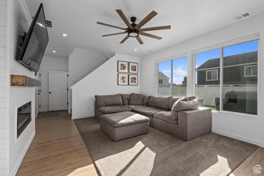 Living room with ceiling fan, hardwood / wood-style flooring, and a textured ceiling