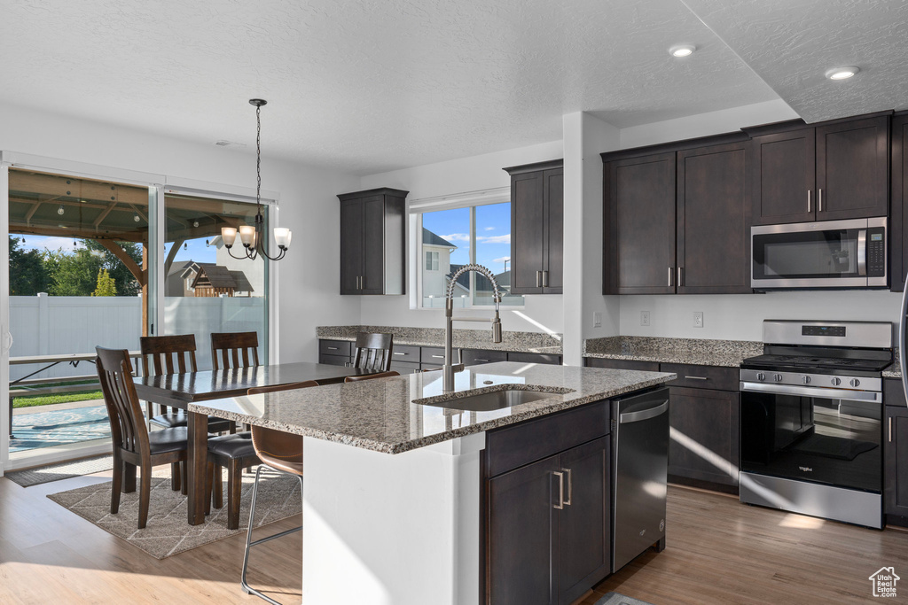 Kitchen featuring a textured ceiling, sink, a kitchen island, appliances with stainless steel finishes, and hardwood / wood-style floors