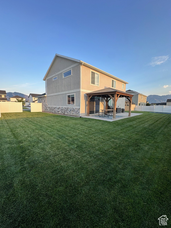 Back of property with a gazebo, a yard, and a patio area