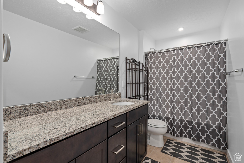 Bathroom with walk in shower, vanity, tile patterned flooring, and toilet