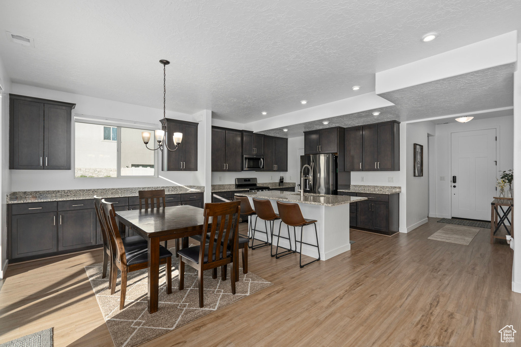 Dining area with a textured ceiling, light hardwood / wood-style flooring, and a chandelier