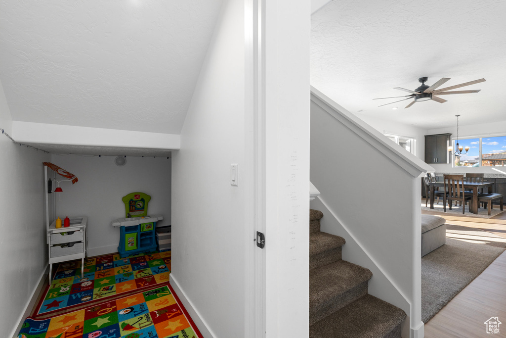 Stairs featuring ceiling fan with notable chandelier, a textured ceiling, and hardwood / wood-style flooring