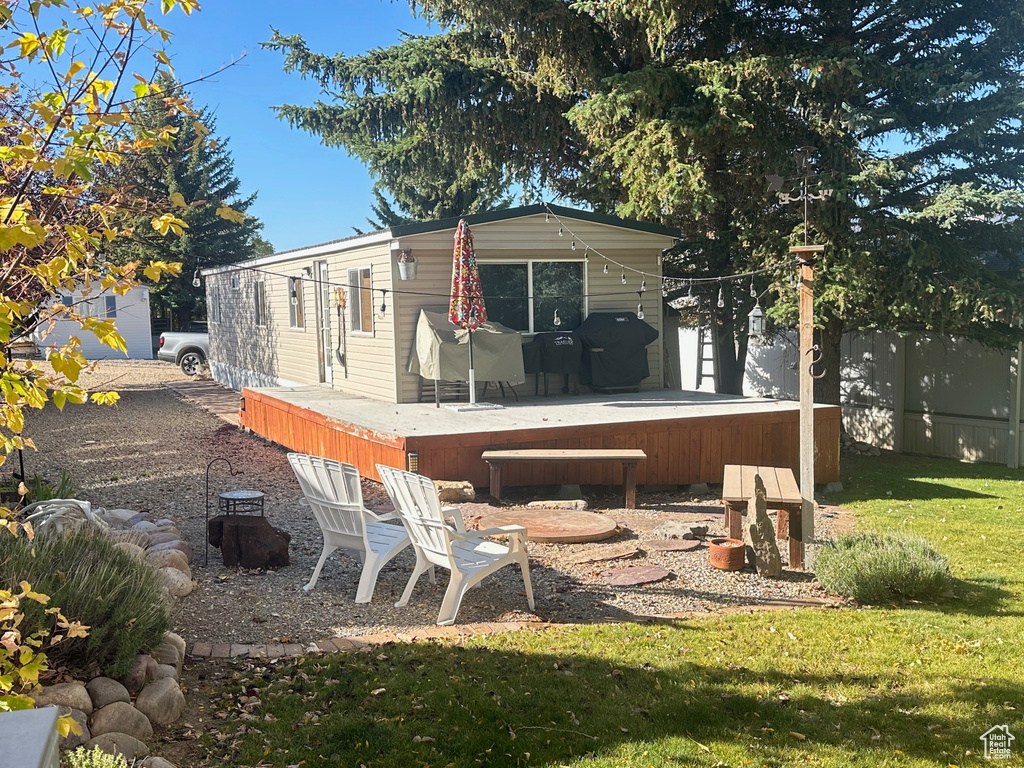 Back of house with a yard, a deck, and a jacuzzi