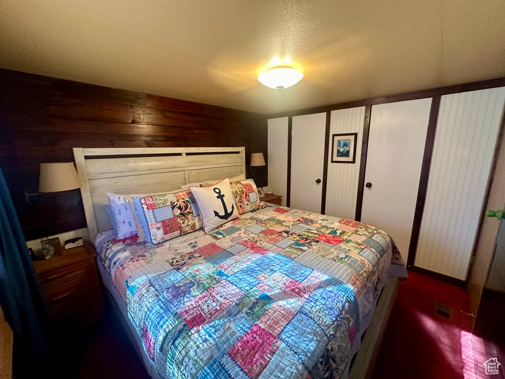 Carpeted bedroom with a textured ceiling and wooden walls