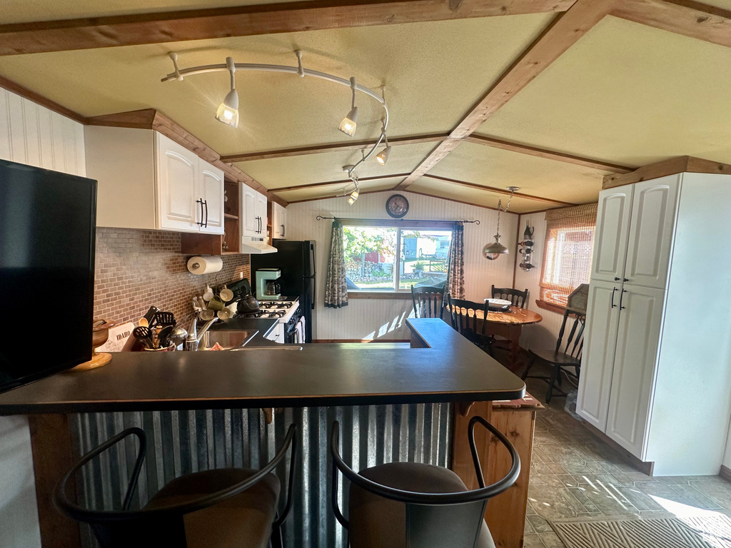 Kitchen with white cabinets, a kitchen bar, lofted ceiling with beams, and kitchen peninsula