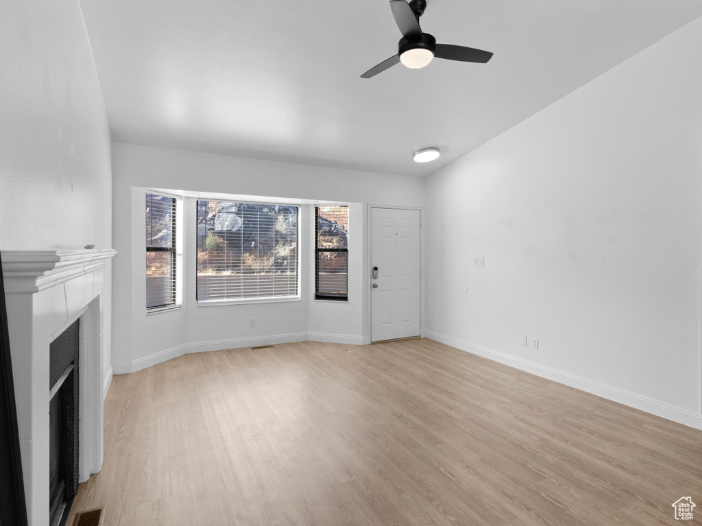 Unfurnished living room featuring ceiling fan and light wood-type flooring