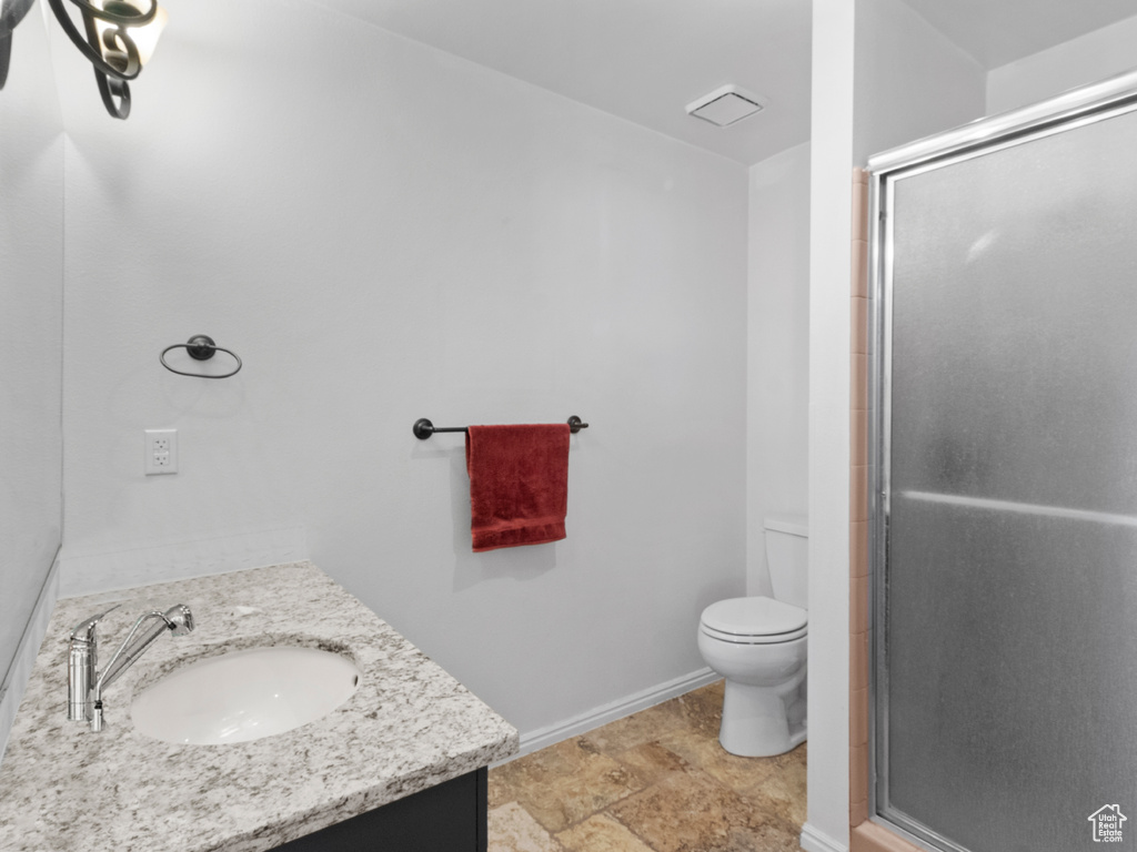 Bathroom featuring walk in shower, vanity, and toilet