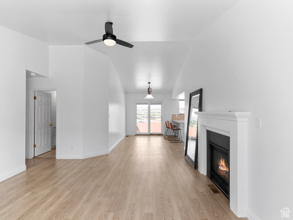 Unfurnished living room featuring light hardwood / wood-style floors, lofted ceiling, and ceiling fan