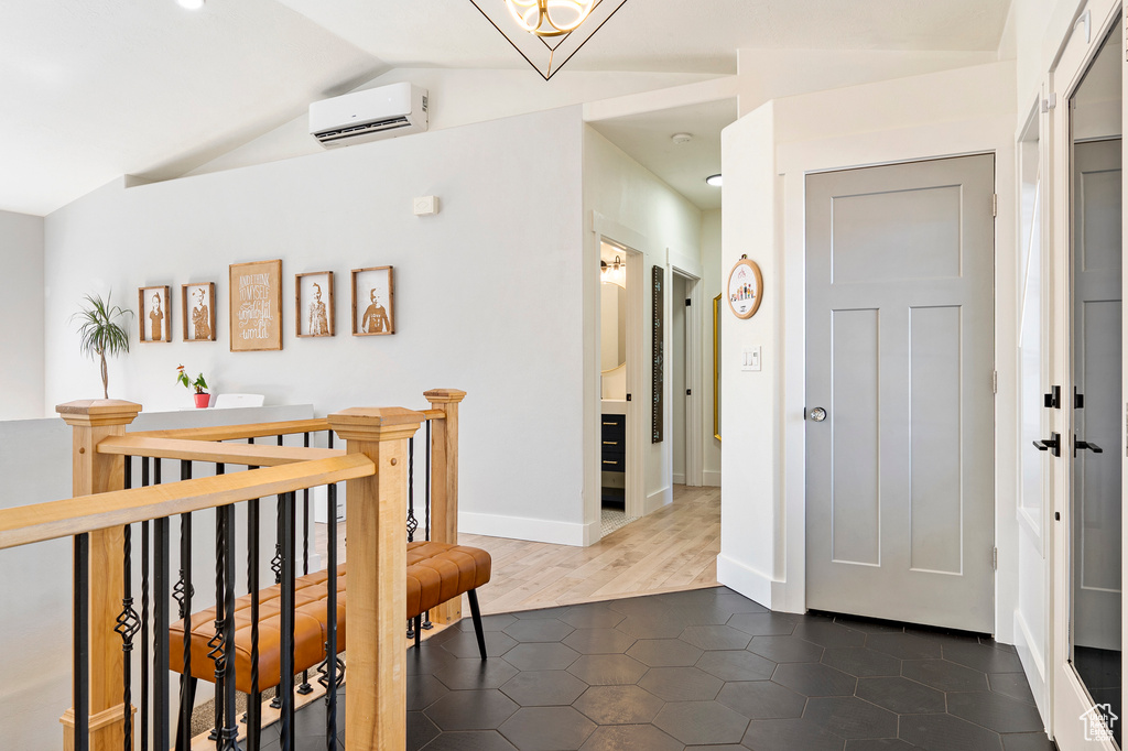 Hall featuring vaulted ceiling, an AC wall unit, and dark wood-type flooring