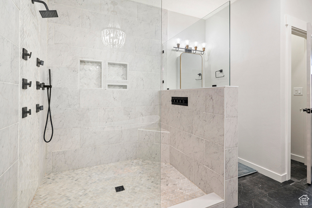 Bathroom with a tile shower and an inviting chandelier