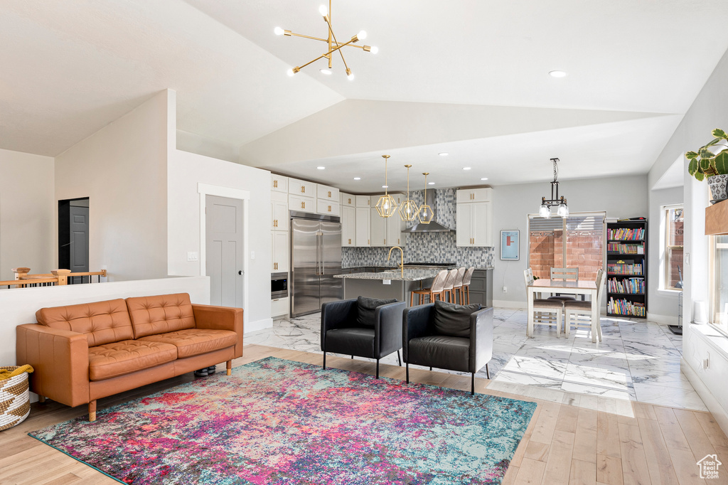 Living room with light wood-type flooring, vaulted ceiling, sink, and a chandelier