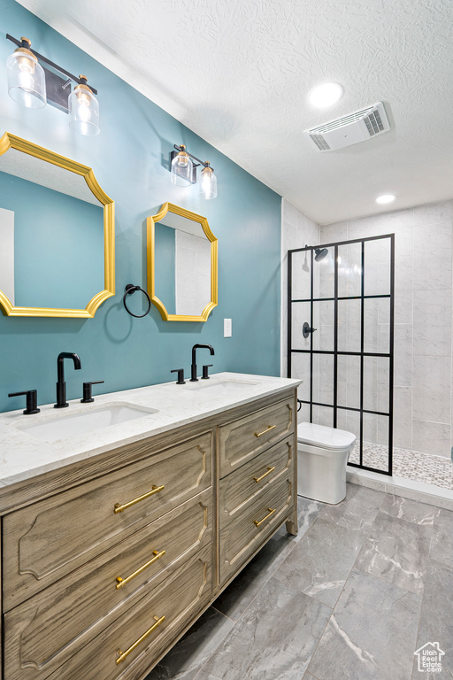 Bathroom with vanity, a textured ceiling, toilet, and a shower with door