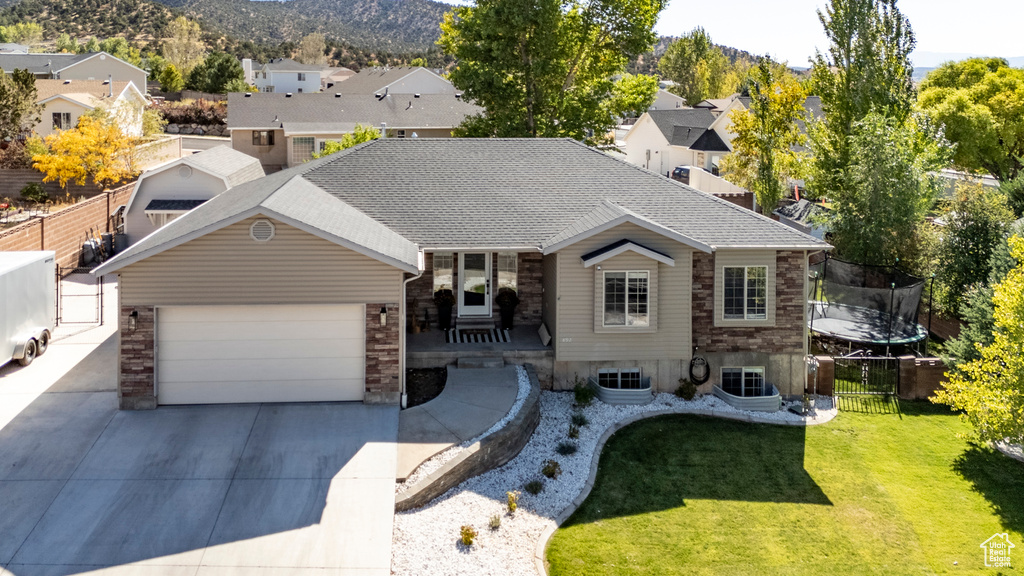 View of front of home featuring a trampoline, a front lawn, a mountain view, and a garage