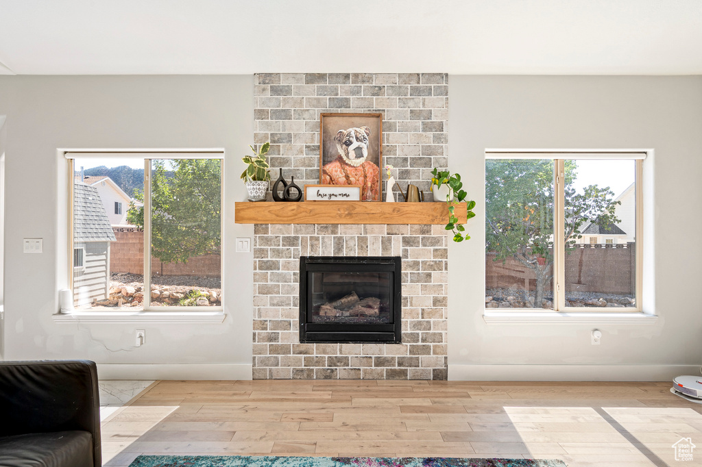 Unfurnished living room featuring hardwood / wood-style floors and a brick fireplace