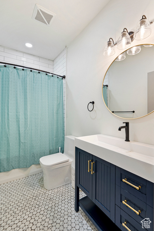 Full bathroom featuring shower / bath combo with shower curtain, tile patterned floors, vanity, and toilet