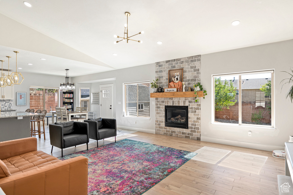 Living room featuring a fireplace, lofted ceiling, light hardwood / wood-style flooring, and plenty of natural light