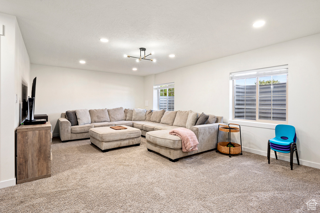 Carpeted living room with an inviting chandelier and a textured ceiling