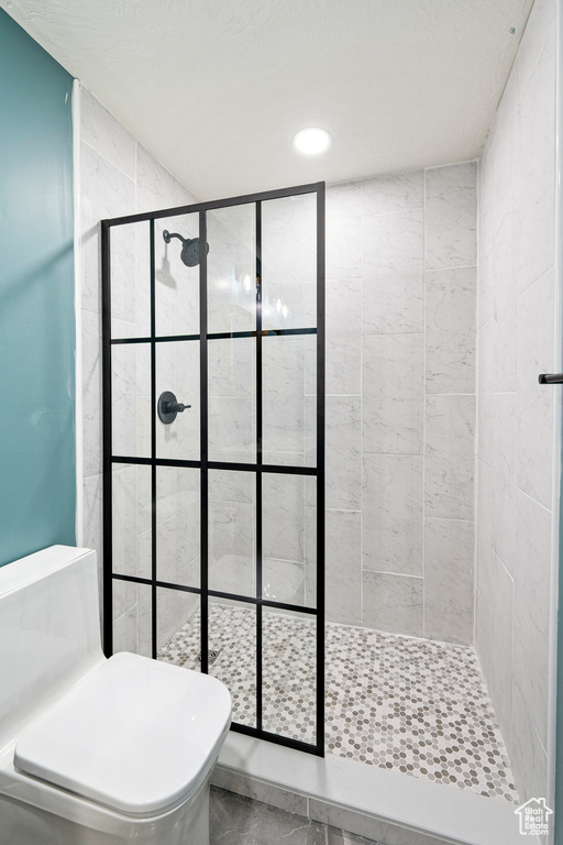 Bathroom featuring tiled shower and toilet