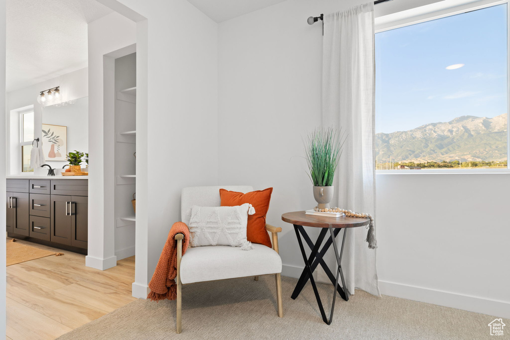 Sitting room with light wood-type flooring, a mountain view, and a healthy amount of sunlight