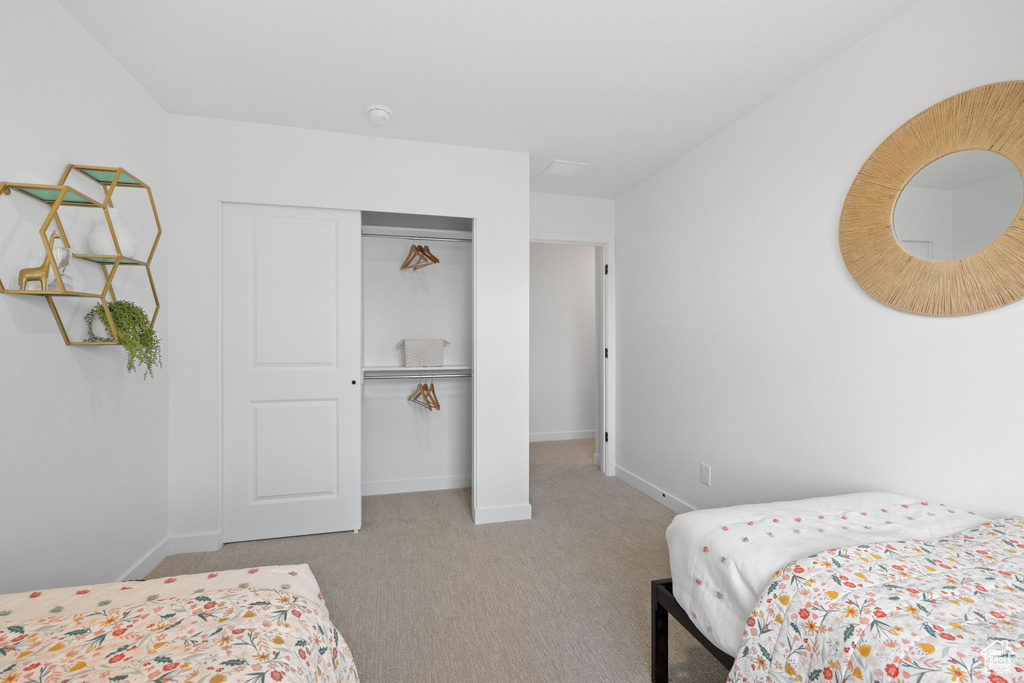 Bedroom with light carpet and a closet