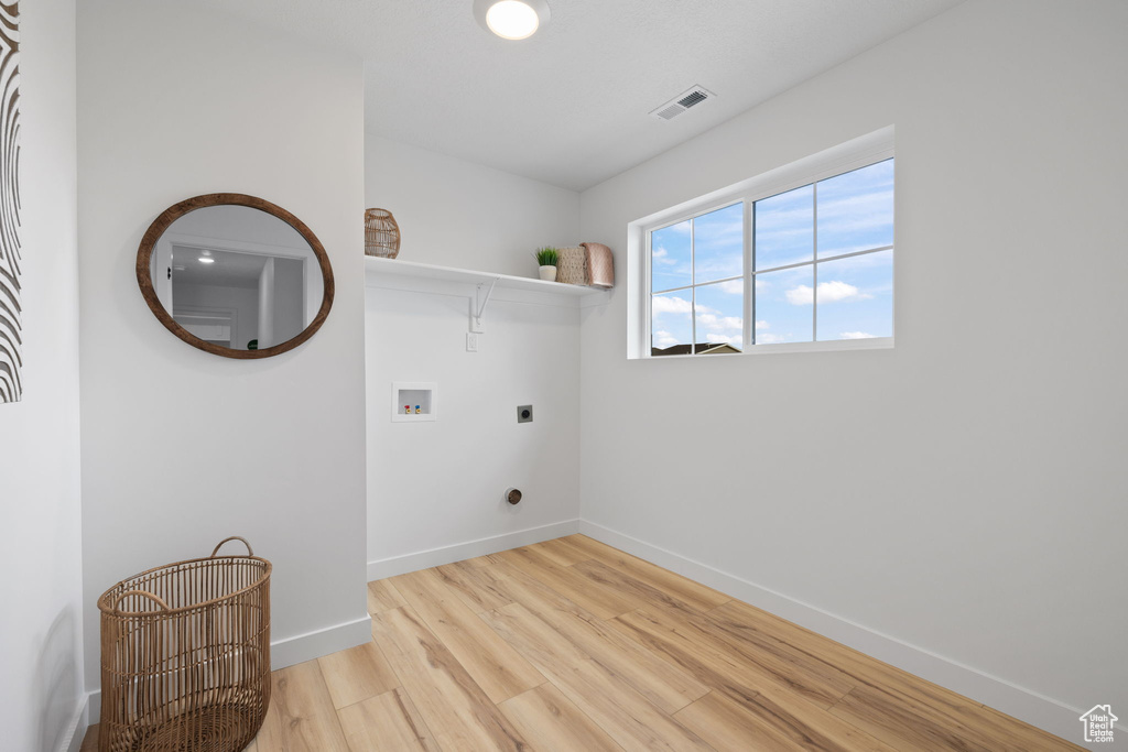 Laundry room featuring hookup for a washing machine, light hardwood / wood-style floors, and electric dryer hookup