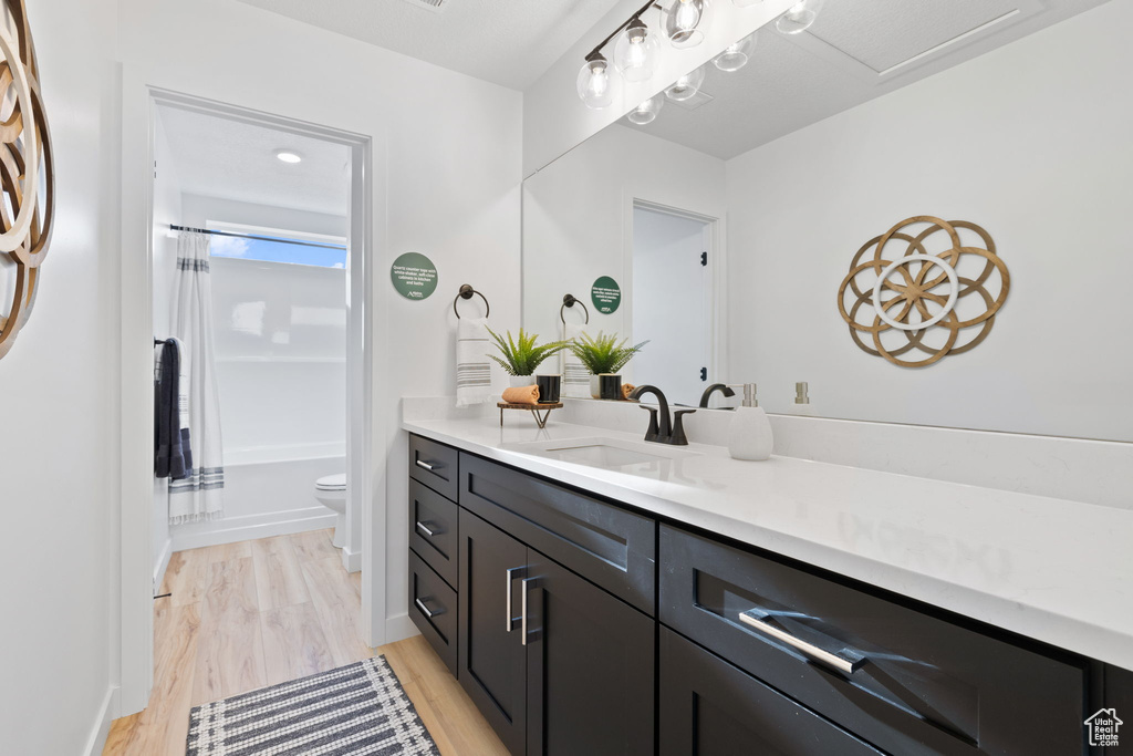 Full bathroom featuring hardwood / wood-style floors, vanity, toilet, and shower / bath combination with curtain