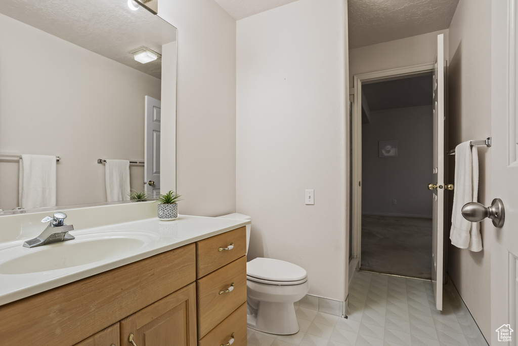 Bathroom with vanity, toilet, and a textured ceiling