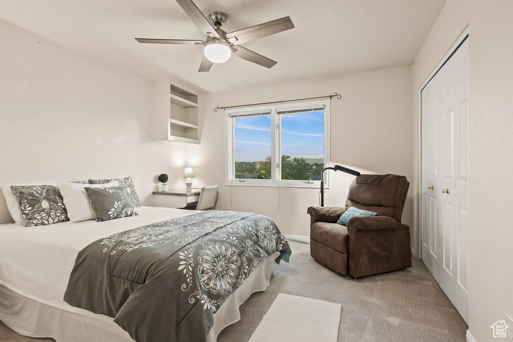 Carpeted bedroom featuring ceiling fan and a closet