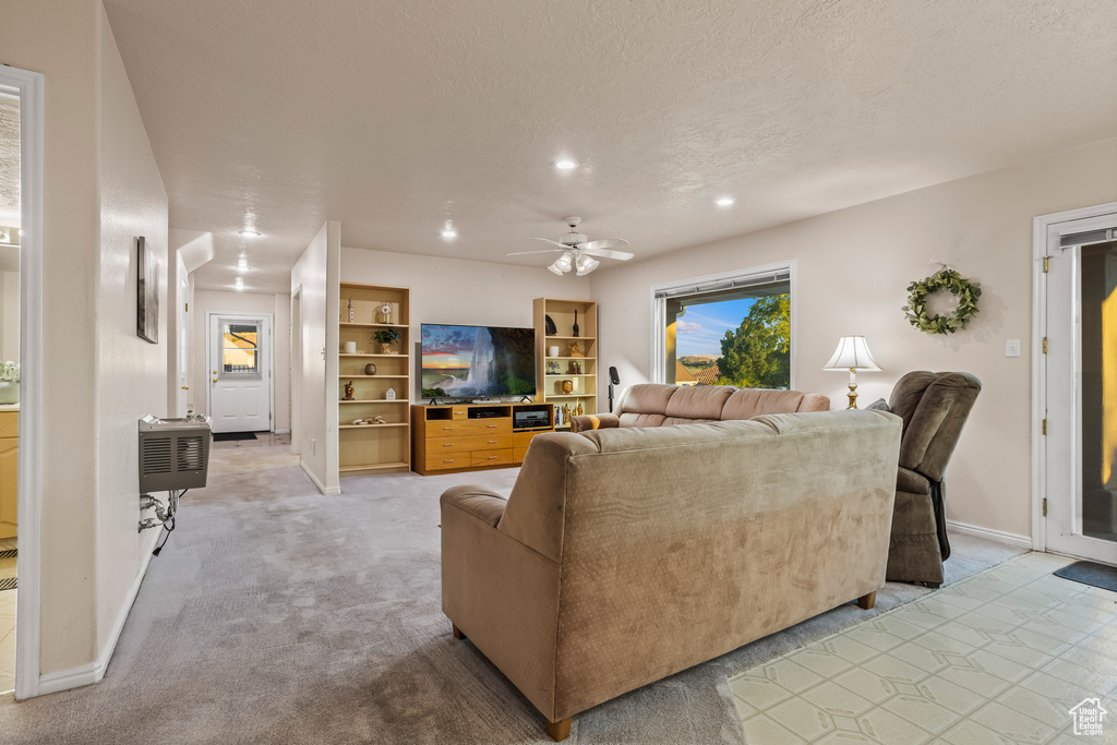 Living room with ceiling fan, light colored carpet, and a textured ceiling