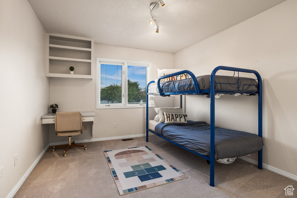 Carpeted bedroom featuring track lighting