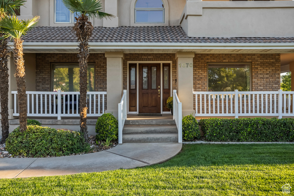 Entrance to property with a porch and a lawn