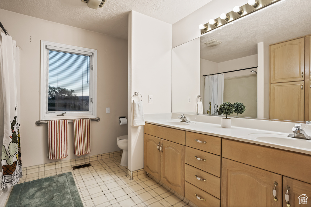 Bathroom with a shower with shower curtain, a textured ceiling, vanity, and toilet