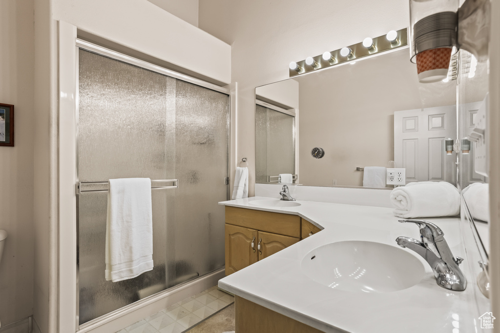 Bathroom featuring tile patterned floors, walk in shower, and vanity