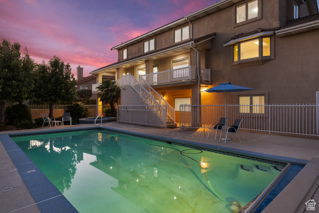 Pool at dusk featuring a patio