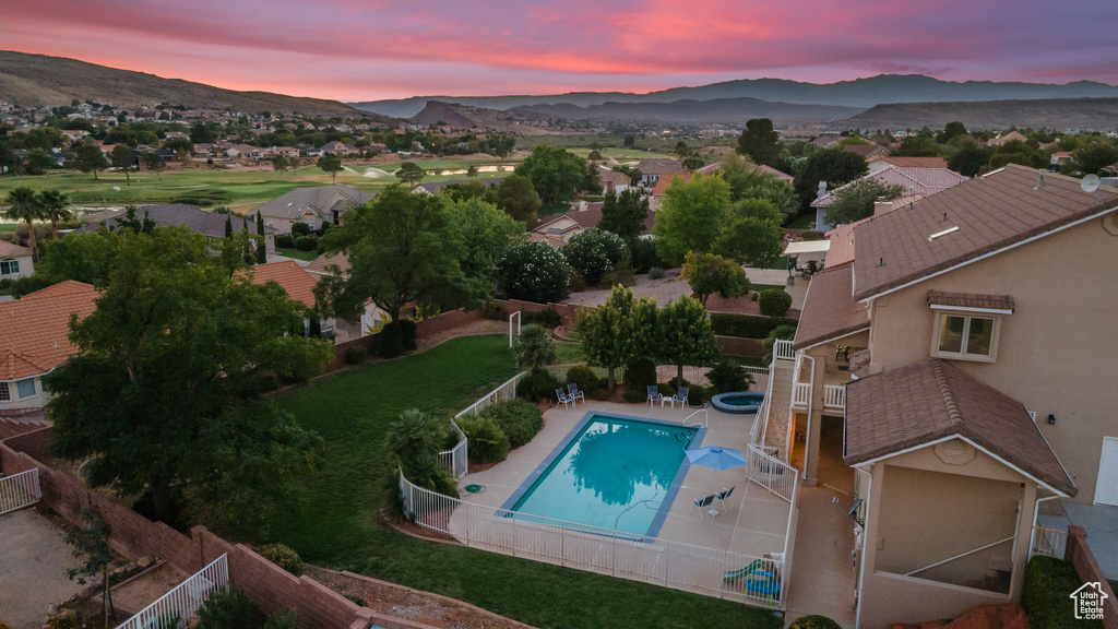 Pool at dusk featuring a mountain view and a patio