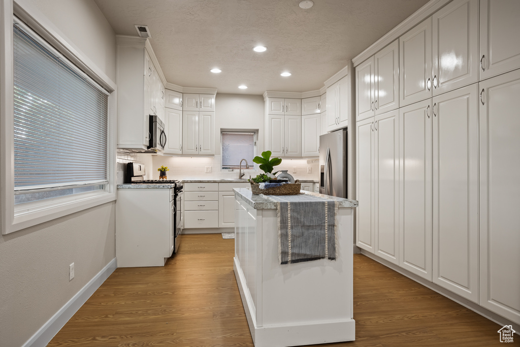 Kitchen featuring white cabinets, light hardwood / wood-style floors, appliances with stainless steel finishes, and sink