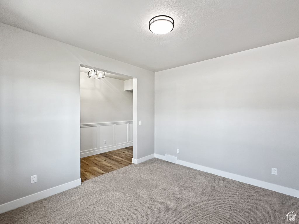 Carpeted spare room featuring an inviting chandelier