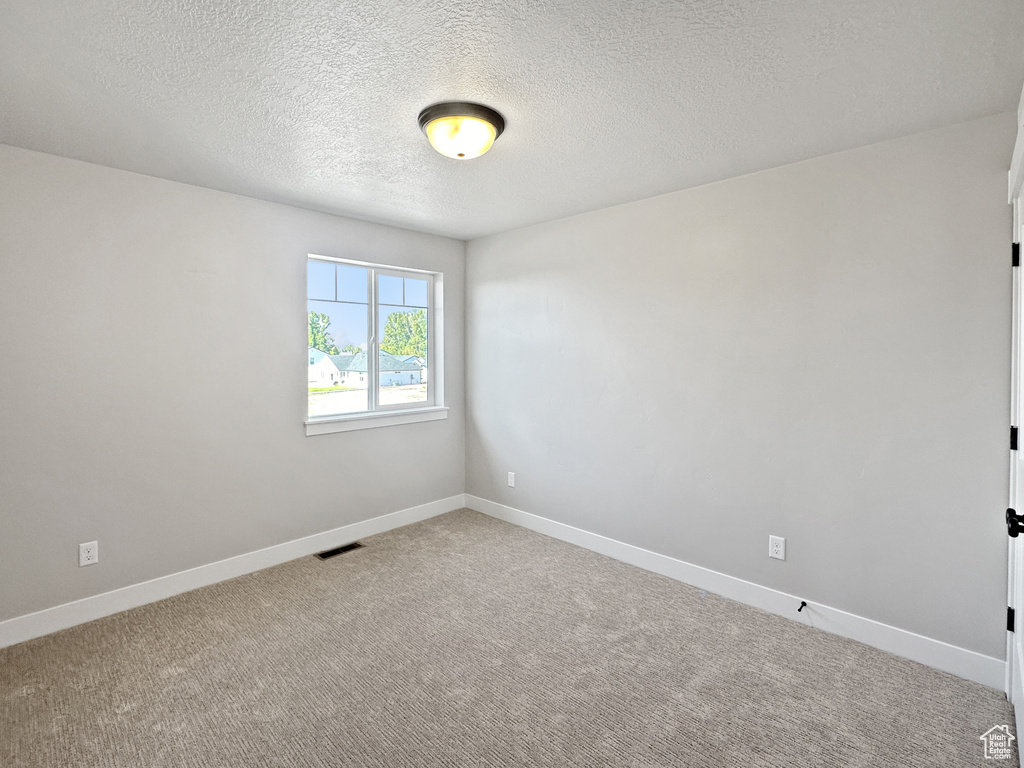 Spare room featuring carpet and a textured ceiling