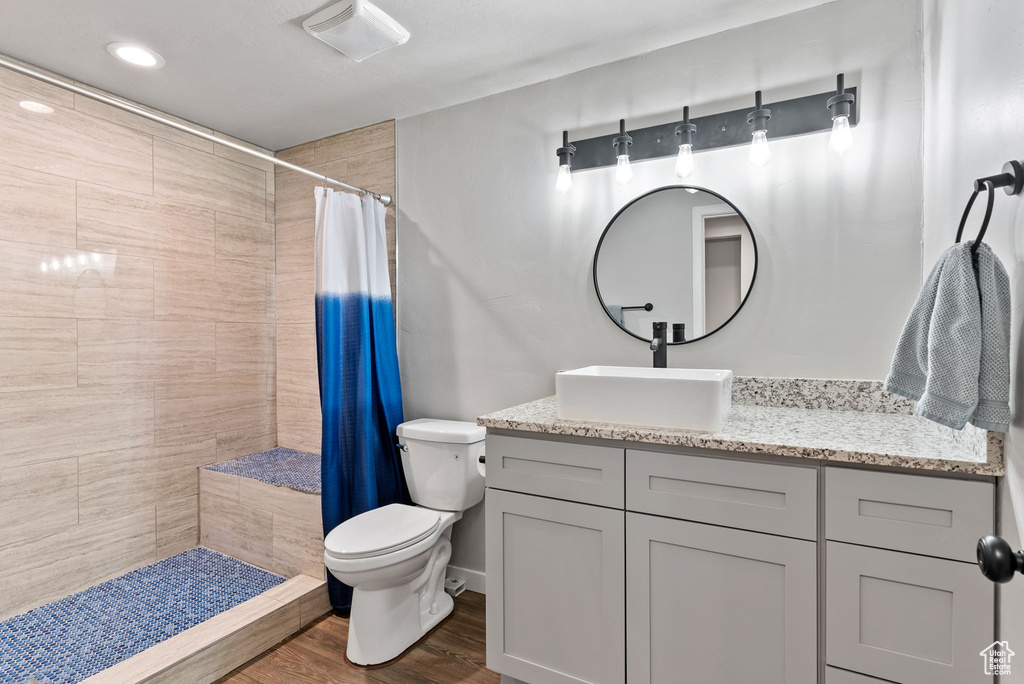 Bathroom with a shower with shower curtain, wood-type flooring, vanity, and toilet