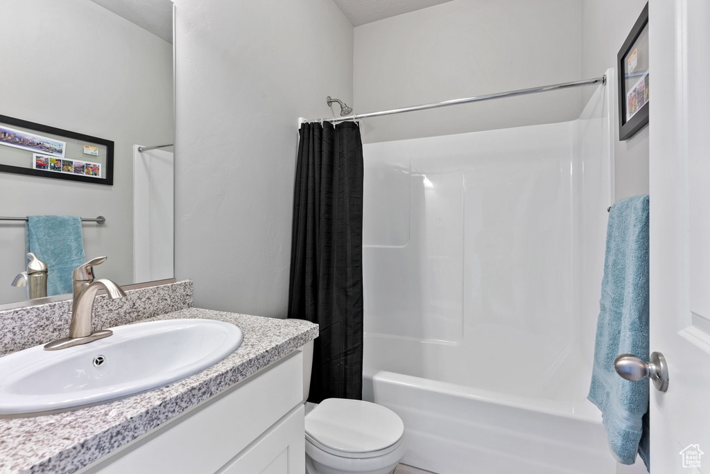 Full bathroom with vanity, shower / tub combo, and toilet