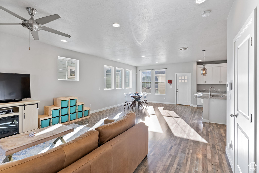 Living room featuring a textured ceiling, dark hardwood / wood-style flooring, ceiling fan, and sink