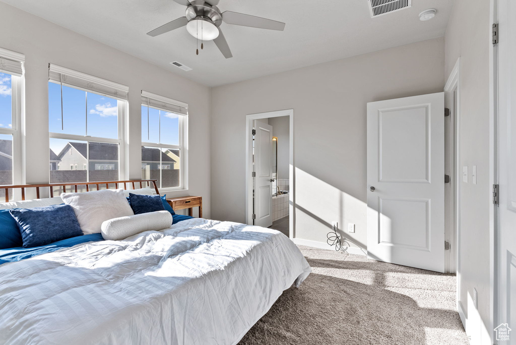 Carpeted bedroom featuring ensuite bath and ceiling fan