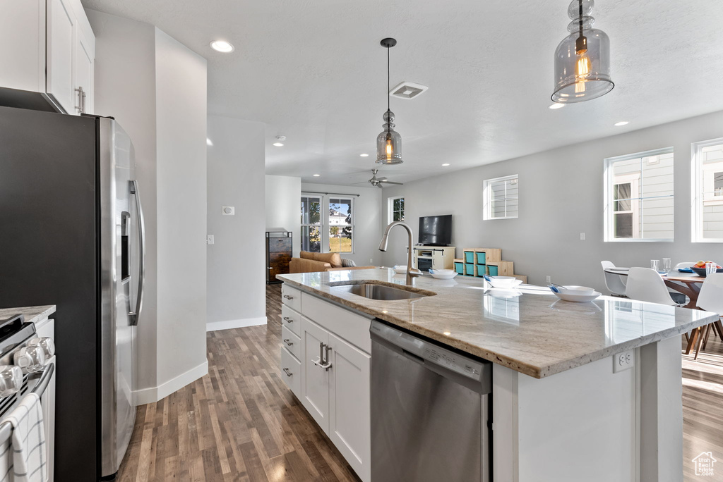 Kitchen with stainless steel appliances, dark wood-type flooring, sink, and white cabinetry