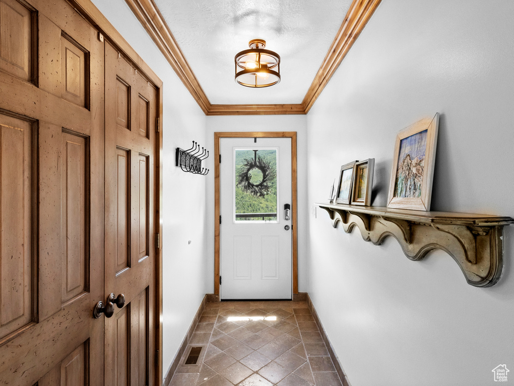 Doorway to outside with a textured ceiling and crown molding