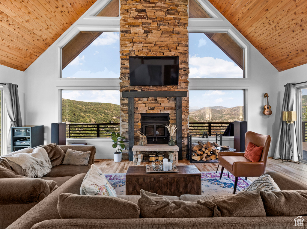 Living room featuring high vaulted ceiling, a wealth of natural light, hardwood / wood-style flooring, and a fireplace