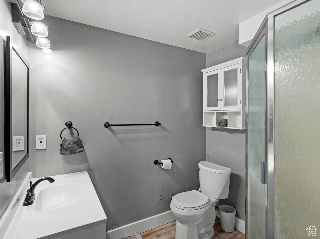 Bathroom featuring vanity, hardwood / wood-style floors, toilet, and a shower with door