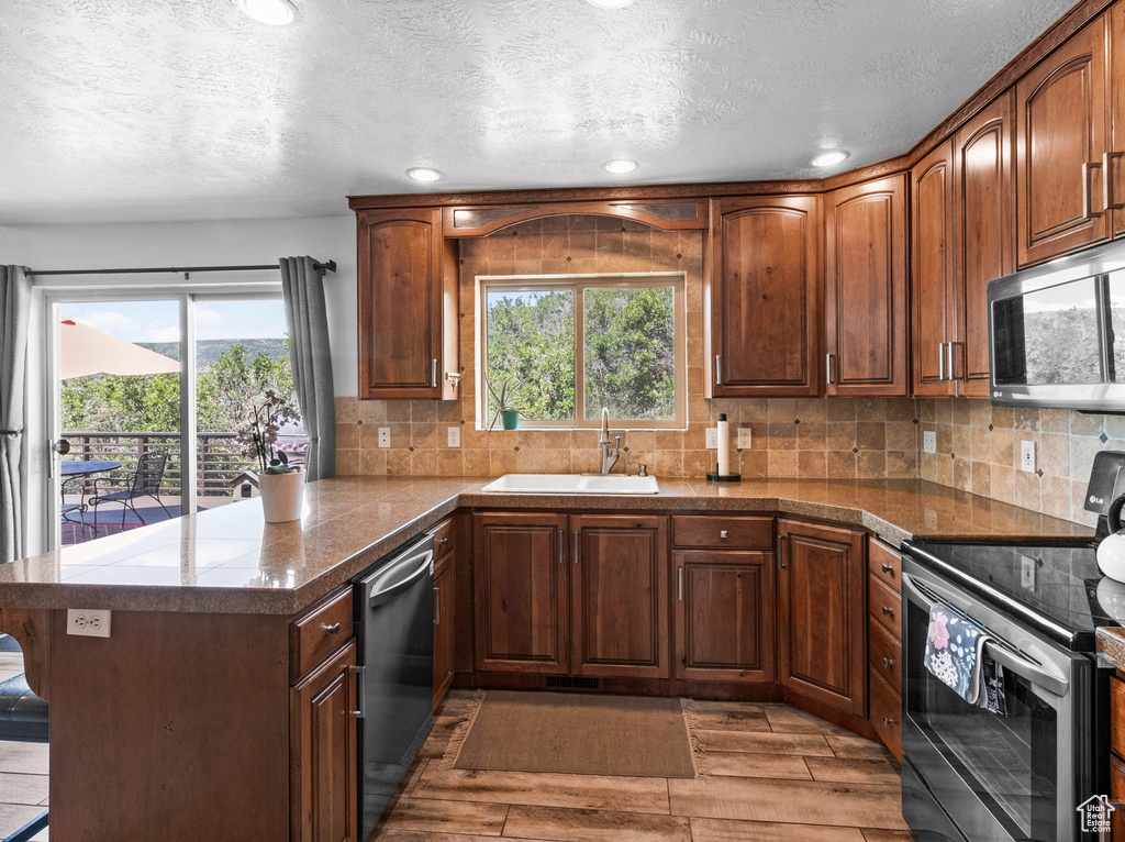 Kitchen with appliances with stainless steel finishes, dark wood-type flooring, sink, and kitchen peninsula