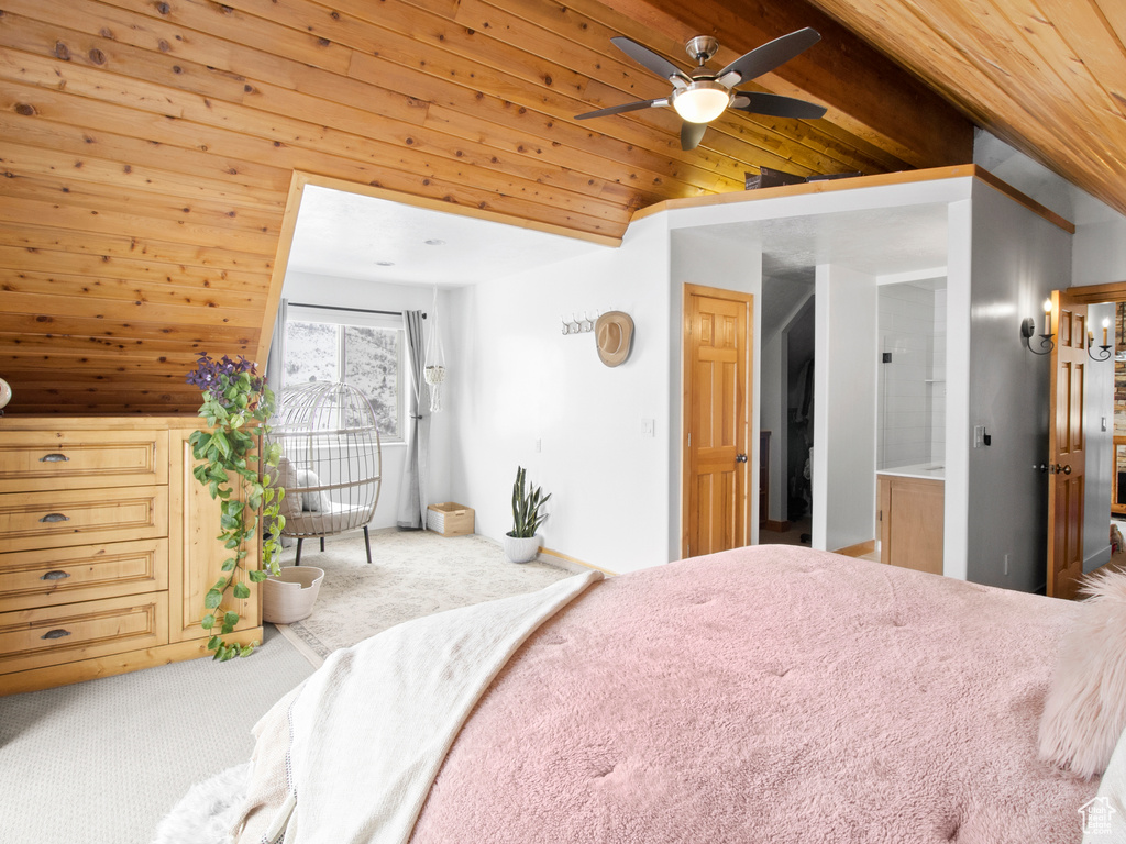 Bedroom featuring carpet, wood ceiling, ensuite bath, and lofted ceiling with beams