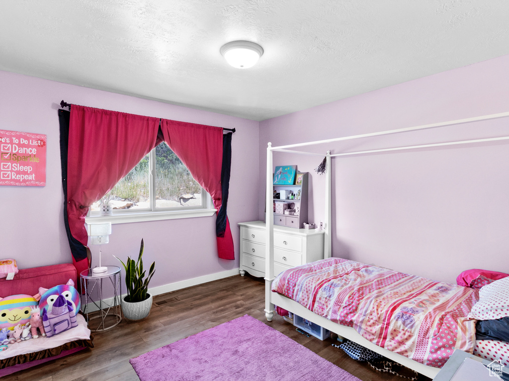 Bedroom with a textured ceiling and hardwood / wood-style flooring