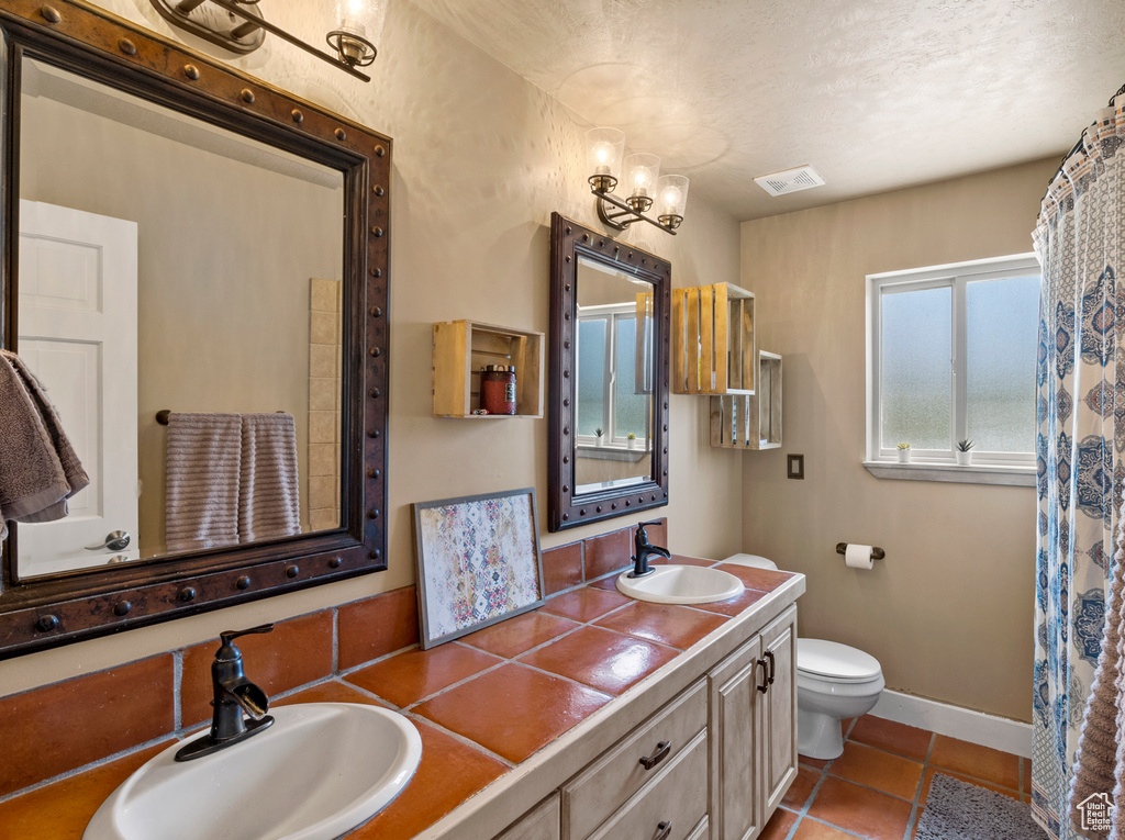 Bathroom featuring a textured ceiling, vanity, toilet, and tile patterned floors